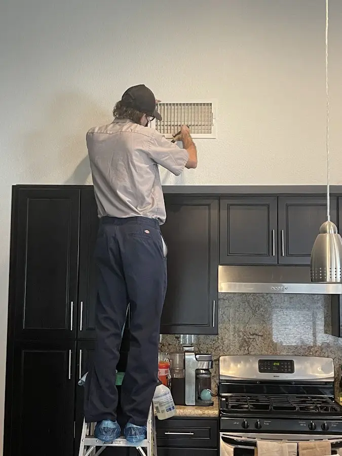 Technician inspecting an air vent during HVAC service in Northvale
